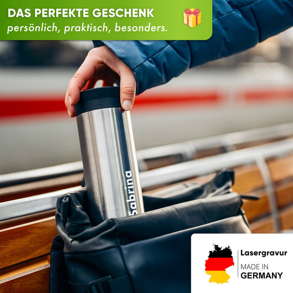 Person storing engraved stainless steel thermobecher in backpack, ideal for coffee or tea on the go, made in Germany.